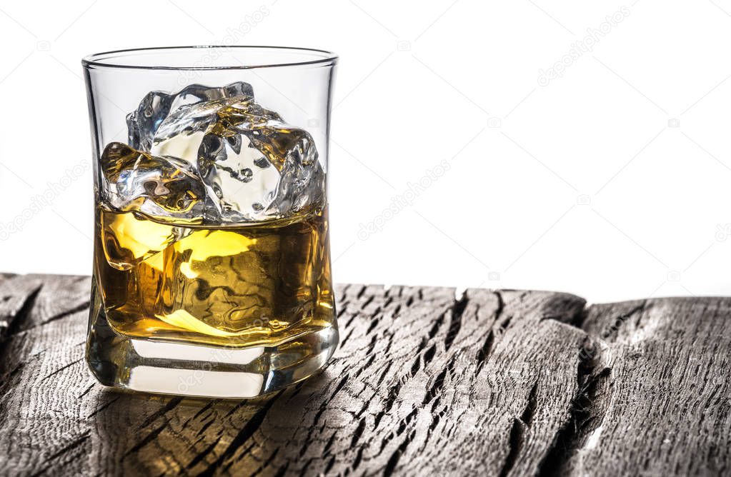 Whiskey glass or glass of whiskey with ice cubes on table at the white background.