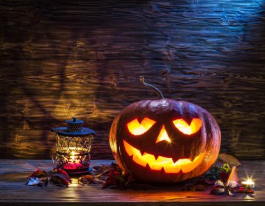 Sırıtan kabak latern veya jack-o'-lantern Cadılar Bayramı sembollerin biridir. Cadılar Bayramı özniteliği. Ahşap arka plan.