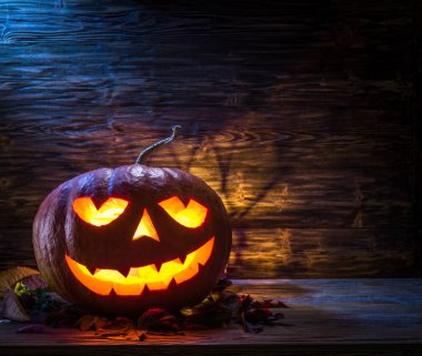 Sırıtan kabak latern veya jack-o'-lantern Cadılar Bayramı sembollerin biridir. Cadılar Bayramı özniteliği. Ahşap arka plan.