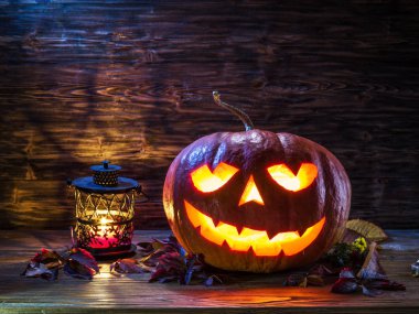 Sırıtan kabak latern veya jack-o'-lantern Cadılar Bayramı sembollerin biridir. Cadılar Bayramı özniteliği. Ahşap arka plan.