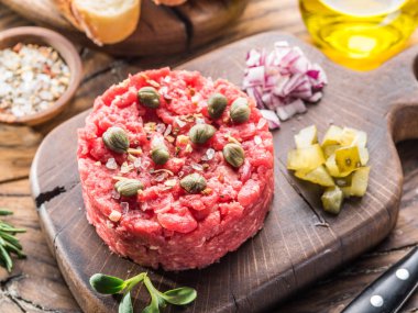 Steak tartare kapari, salatalık turşusu ve doğranmış soğan ile servis.