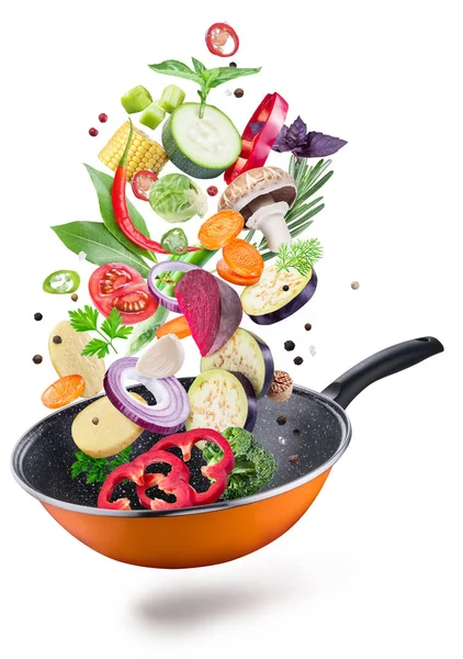 Flying fresh vegetables and spices over a pan. File contains clipping path. Flying motion effect.