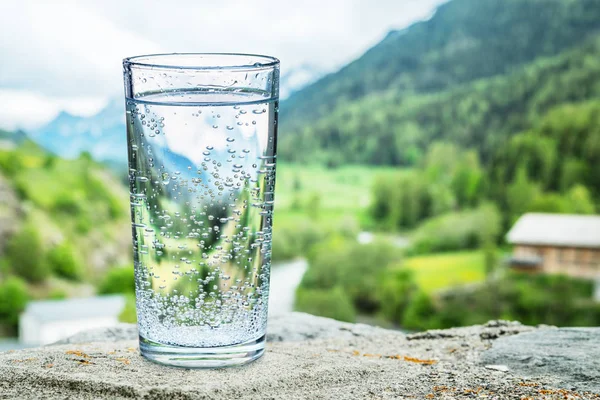Glas Wasser Auf Dem Stein Verschwommene Schneeberge Und Grüne Wälder — Stockfoto