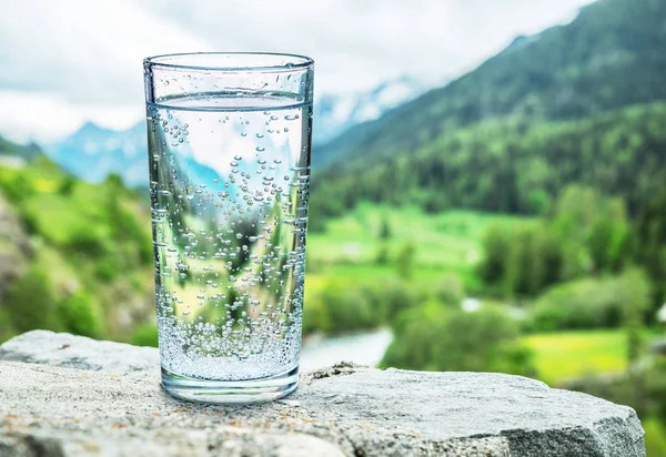 Bicchiere Acqua Sulla Pietra Montagne Neve Sfocate Foreste Verdi Sullo — Foto Stock