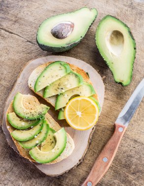 Bir parça limon ile kızarmış ekmek üzerinde avokado dilimleri. Üstten Görünüm.