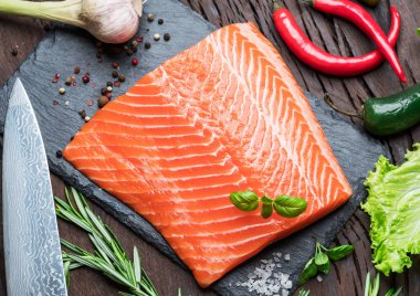 Otlar ve baharatlar ile siyah kesme tahtası üzerinde taze somon fileto. Üstten Görünüm.