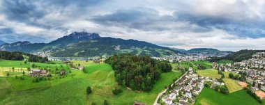 Village Horn, Mount Pilatus, Switzerland, May 13, 2018. Panorama green spring fields and cloudy sky. clipart