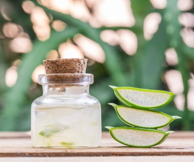 Ahşap masadaki kozmetik kavanozunda taze aloe yaprakları ve aloe jeli..