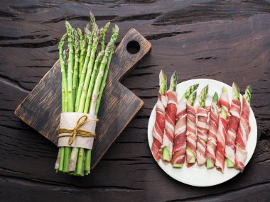 Yeşil kuşkonmaz lahanası ahşap masa jambon sarılı. Üstten görünüm.