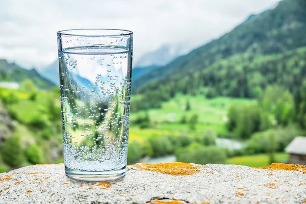 Glas Wasser Auf Dem Stein Verschwommene Schneeberge Und Grüne Wälder — Stockfoto