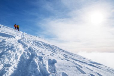 Turistler karla kaplı dağın tepesine doğru yola. Hiking kış.