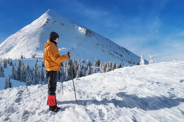 Winter hiking. Tourist on snowy mountain top enjoying beautiful view of nature.