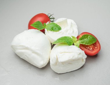 Geleneksel İtalyan mozzarella peyniri otlar ve gri arka plan üzerinde domates ile.