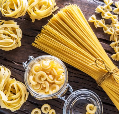 Different pasta types on the wooden  table. Top view. clipart