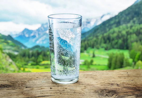 Bicchiere Acqua Sulla Pietra Montagne Neve Sfocate Foreste Verdi Sullo — Foto Stock