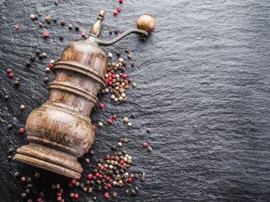 Renkli peppercorns ve siyah arka plan üzerine eski karabiber değirmeni. 