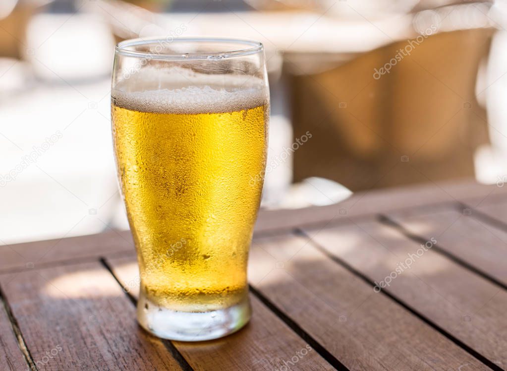 Glass of light beer on the wooden table.