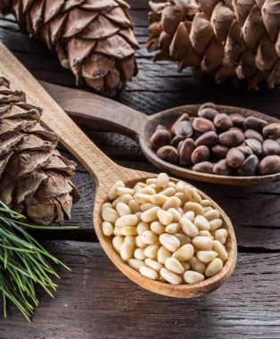 Çam fıstığı ahşap masa üzerinde kaşık ve çam fıstığı koni. Organik gıda.