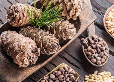 Çam fıstığı ahşap masa üzerinde kaşık ve çam fıstığı koni. Organik gıda.