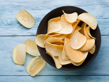 Potato chips on a blue wooden background. clipart