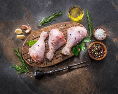 Baharat ve tuzlu tavuk bacakları kesim tahtasında pişirmeye hazır..