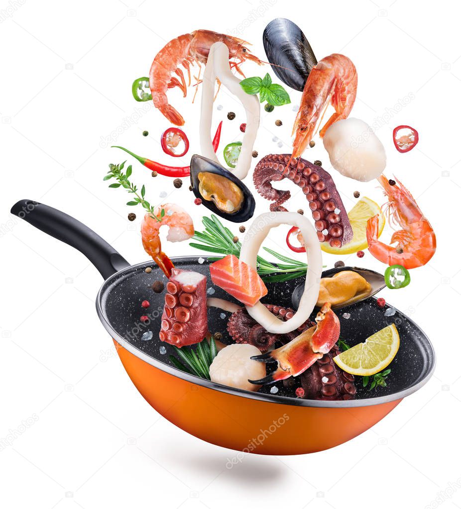 Flying seafood with spices falling into a frying pan. Flying motion effect of cooking process. File contains clipping path.