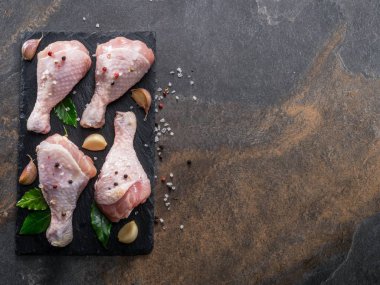 Baharat ve tuzlu tavuk bacakları kesim tahtasında pişirmeye hazır..