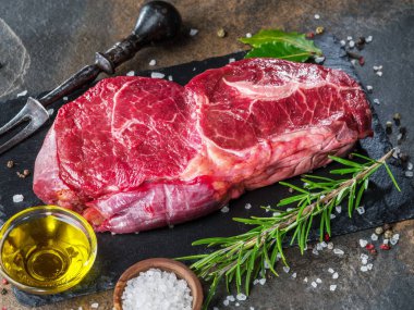 Ham antrikot biftek veya sığır eti biftek grafit kesme tahtası otlar ve baharatlar ile. Üstten görünüm.