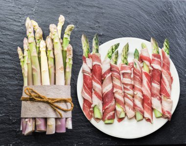 Yeşil kuşkonmaz lahanası grafit zemin üzerine jambon sarılı. Üstten görünüm.