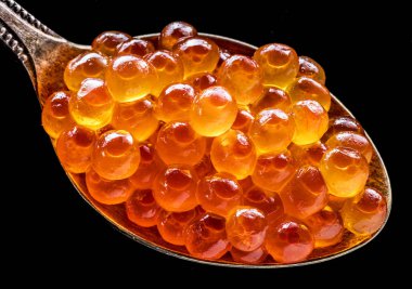 Gümüş kaşık siyah zemin üzerine kırmızı havyar. Makro resim.