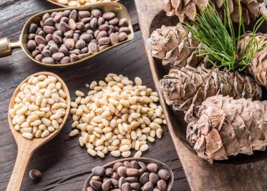 Çam fıstığı ahşap masa üzerinde kaşık ve çam fıstığı koni. Organik gıda.