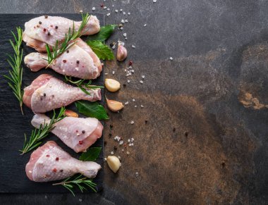 Baharat ve tuzlu tavuk bacakları kesim tahtasında pişirmeye hazır..