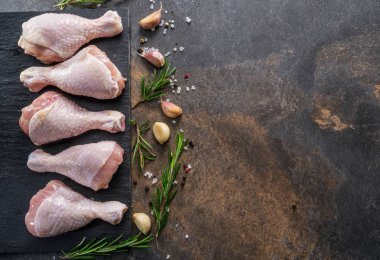 Baharat ve tuzlu tavuk bacakları kesim tahtasında pişirmeye hazır..