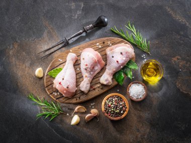 Baharat ve tuzlu tavuk bacakları kesim tahtasında pişirmeye hazır..