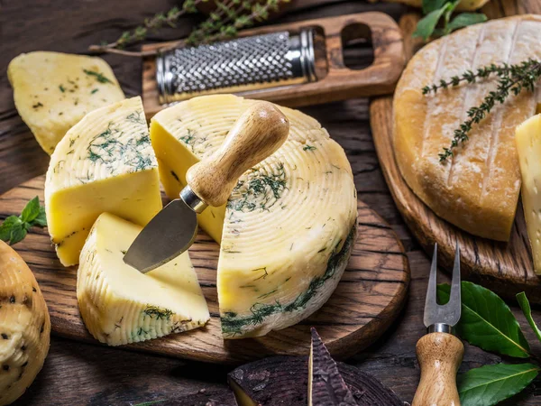 木製の背景にカトラリーとハーブとチーズのホイール チーズの背景 — ストック写真