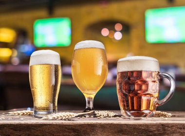 Ahşap masa bira gözlük. Arka plan bulanık pub iç.