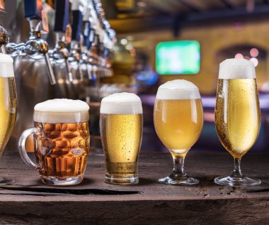 Soğutulmuş kupalar ve eski ahşap masa bira gözlük. Pub iç ve bar counter bira ile arka plan musluklar. Bira çeşitleri.