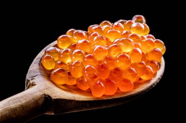 Tahta kaşık siyah zemin üzerine kırmızı havyar. Makro resim.