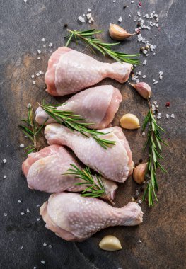 Baharat ve tuzlu tavuk bacakları kesim tahtasında pişirmeye hazır..