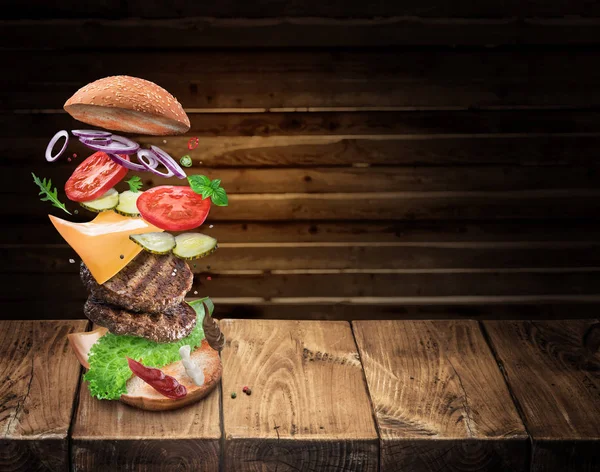 Hamburger malzemeler tek mükemmel bir yemek oluşturmak için bir düşüyor. Burger pişirme renkli kavramsal resim.