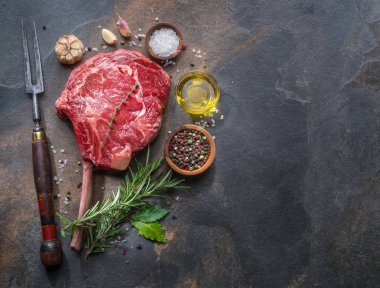 Ham antrikot biftek veya sığır eti biftek grafit kesme tahtası otlar ve baharatlar ile. Üstten görünüm.