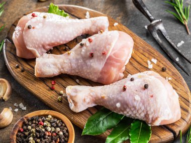 Baharat ve tuzlu tavuk bacakları kesim tahtasında pişirmeye hazır..