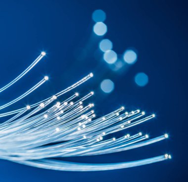 Ucunda ışık olan bir yığın optik iplik. Mavi arkaplan.