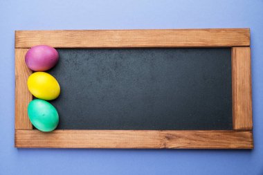 Yazı tahtası ve çevresindeki renkli Paskalya yumurtaları. Yukarıdan görüntülemek.