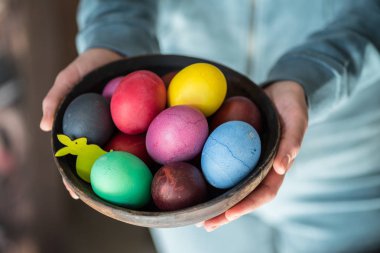 Kadının elinde kase renkli Paskalya yumurtaları. 