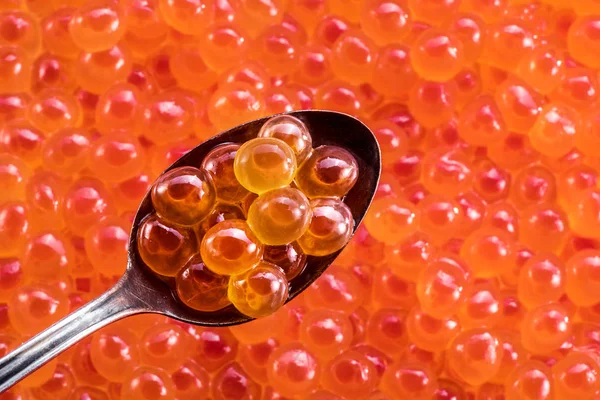 Salmon roe in the silver spoon close-up. Red caviar at the backg — Stock Photo, Image