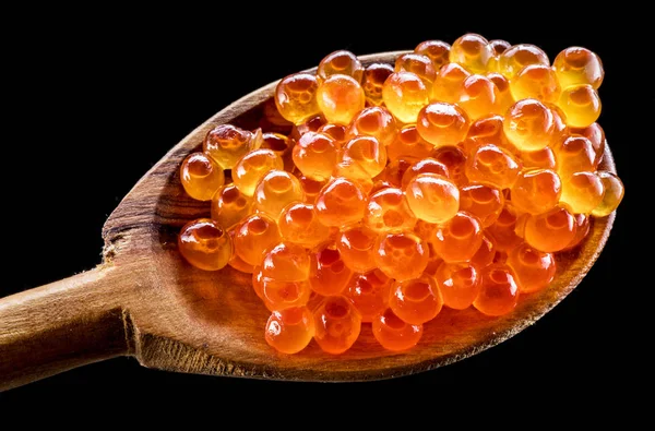 Wooden spoon of red caviar on black background.  Macro picture. — Stock Photo, Image