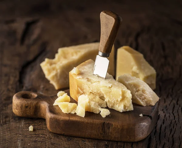 Piece of Parmesan cheese and cheese knife on the wooden board. D — Stock Photo, Image