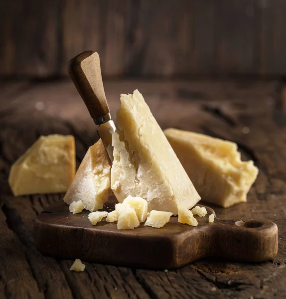 Pedazo de queso parmesano y cuchillo de queso en la tabla de madera. D) — Foto de Stock