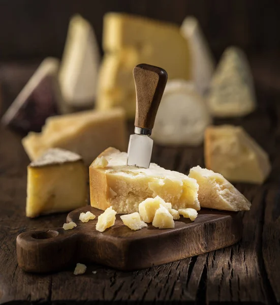 Stukje Parmezaanse kaas op het houten bord. Assortiment van dif — Stockfoto